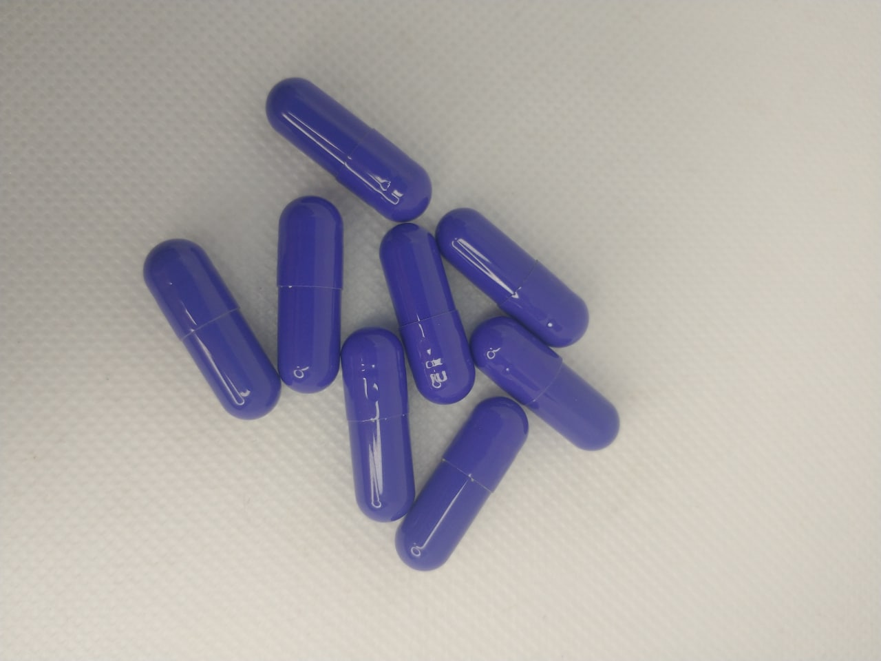Cápsulas roxas do ReduPhine Caps espalhadas em fundo branco