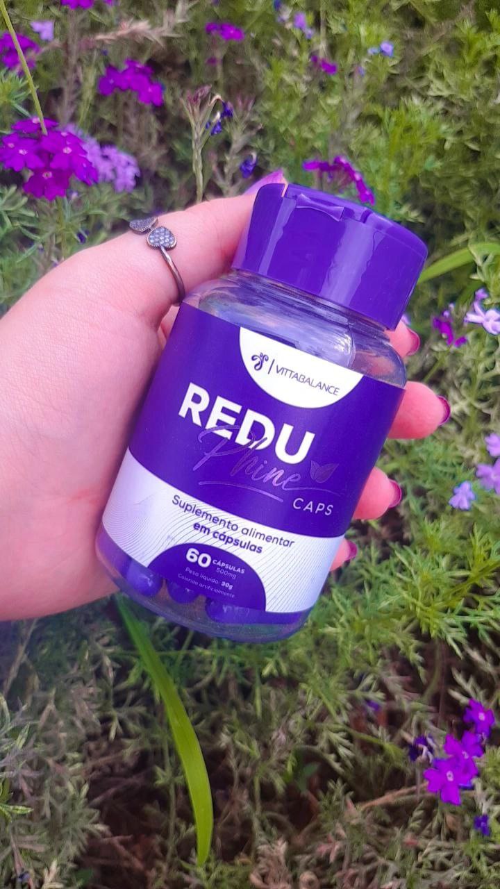 Frasco do ReduPhine Caps na mão com fundo de flores roxas