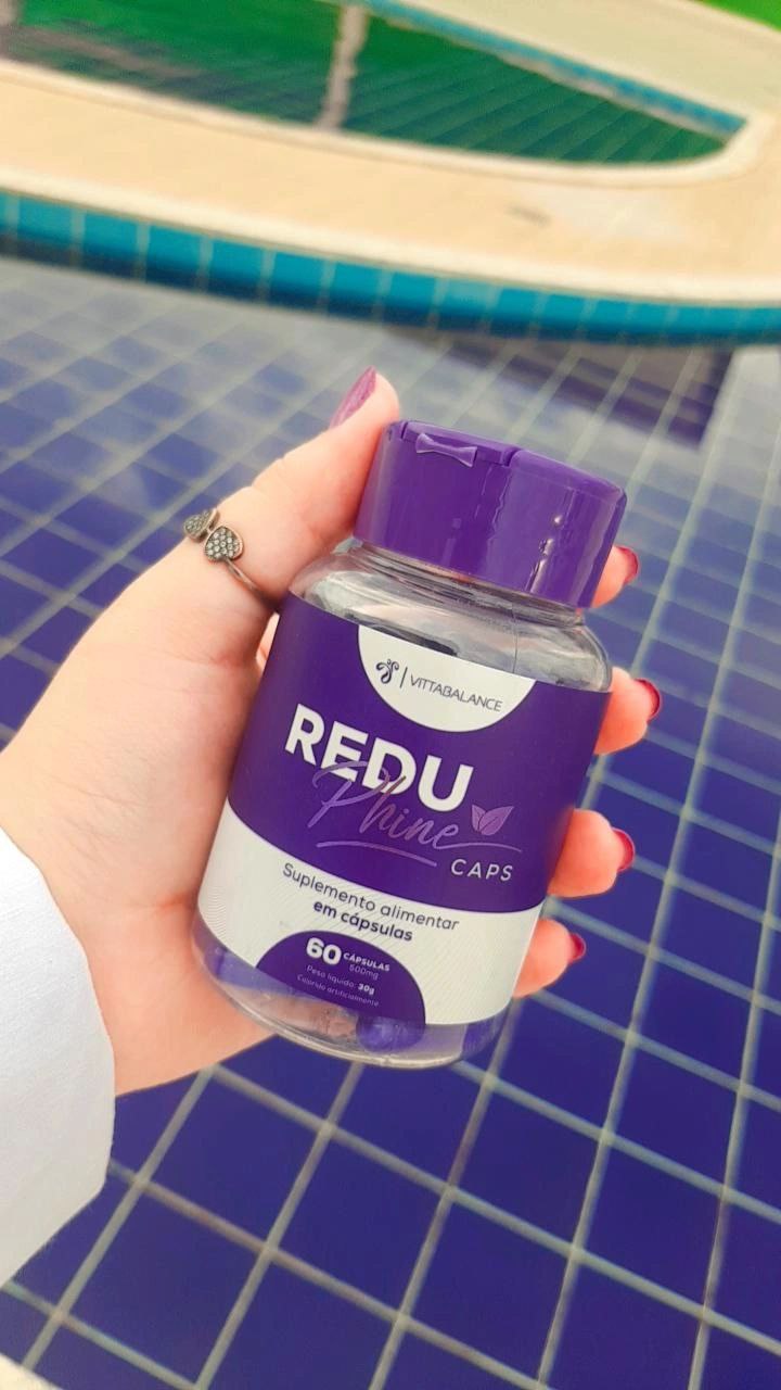 Frasco do ReduPhine Caps na mão com fundo de piscina azul
